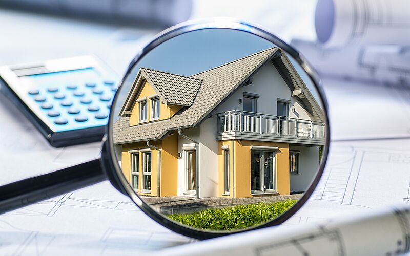 haus in lupe und taschenrechner