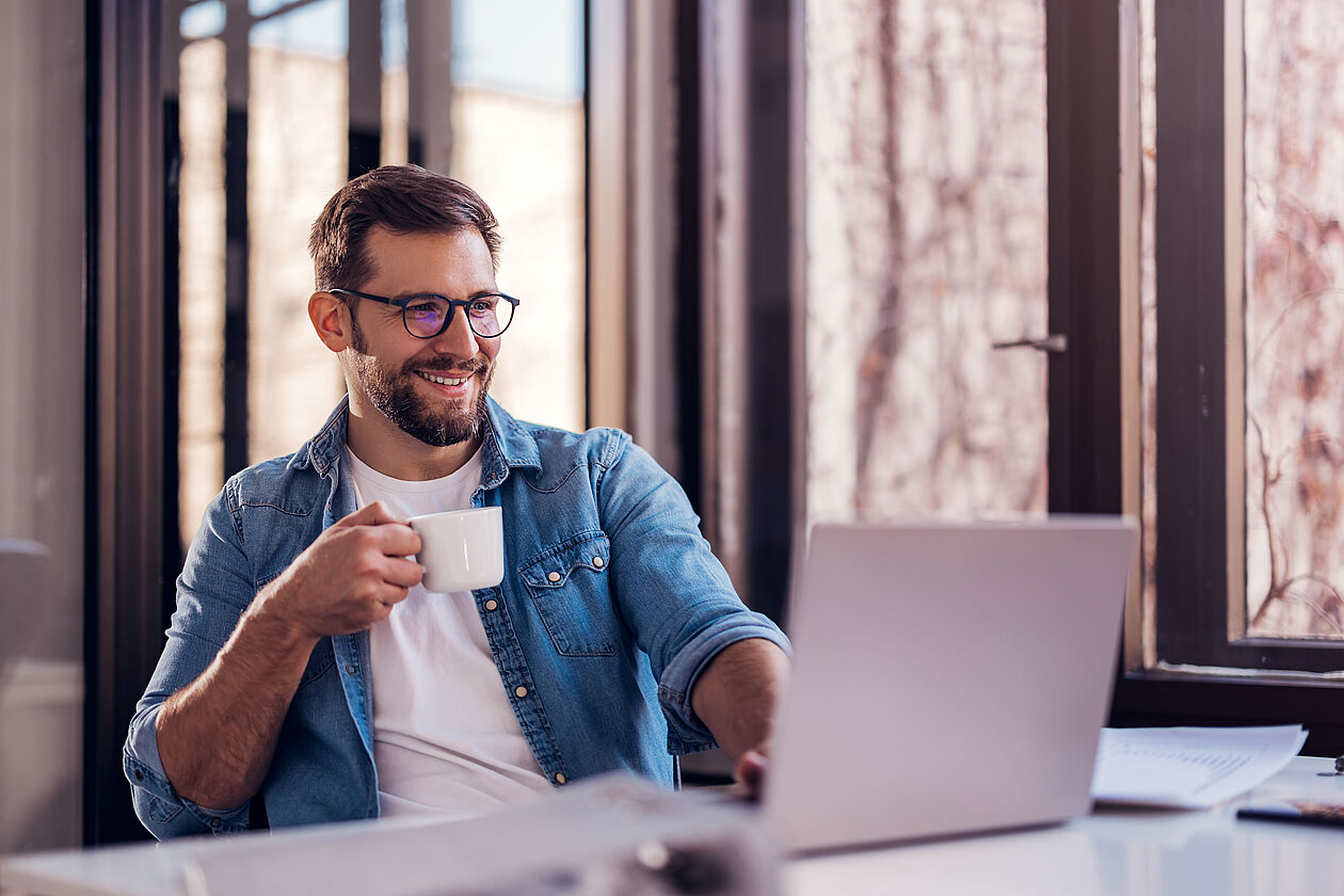 Mann mit kaffee am Laptop