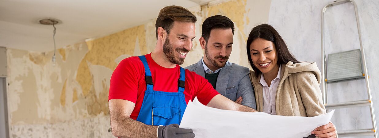 3 Personen halten einen Bauplan