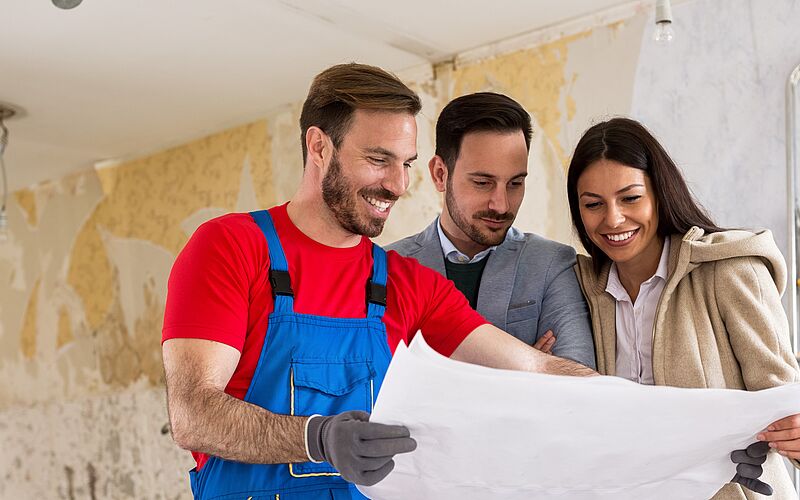 3 Personen halten einen Bauplan