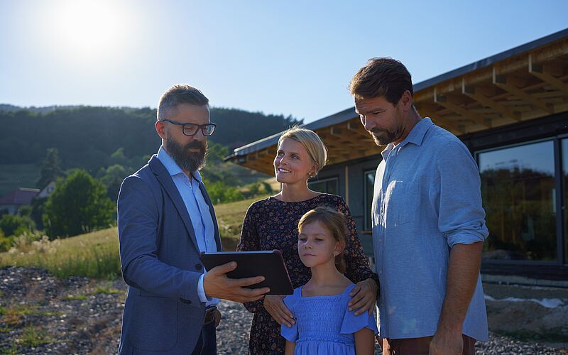 immobilienmakler und familie vor haus