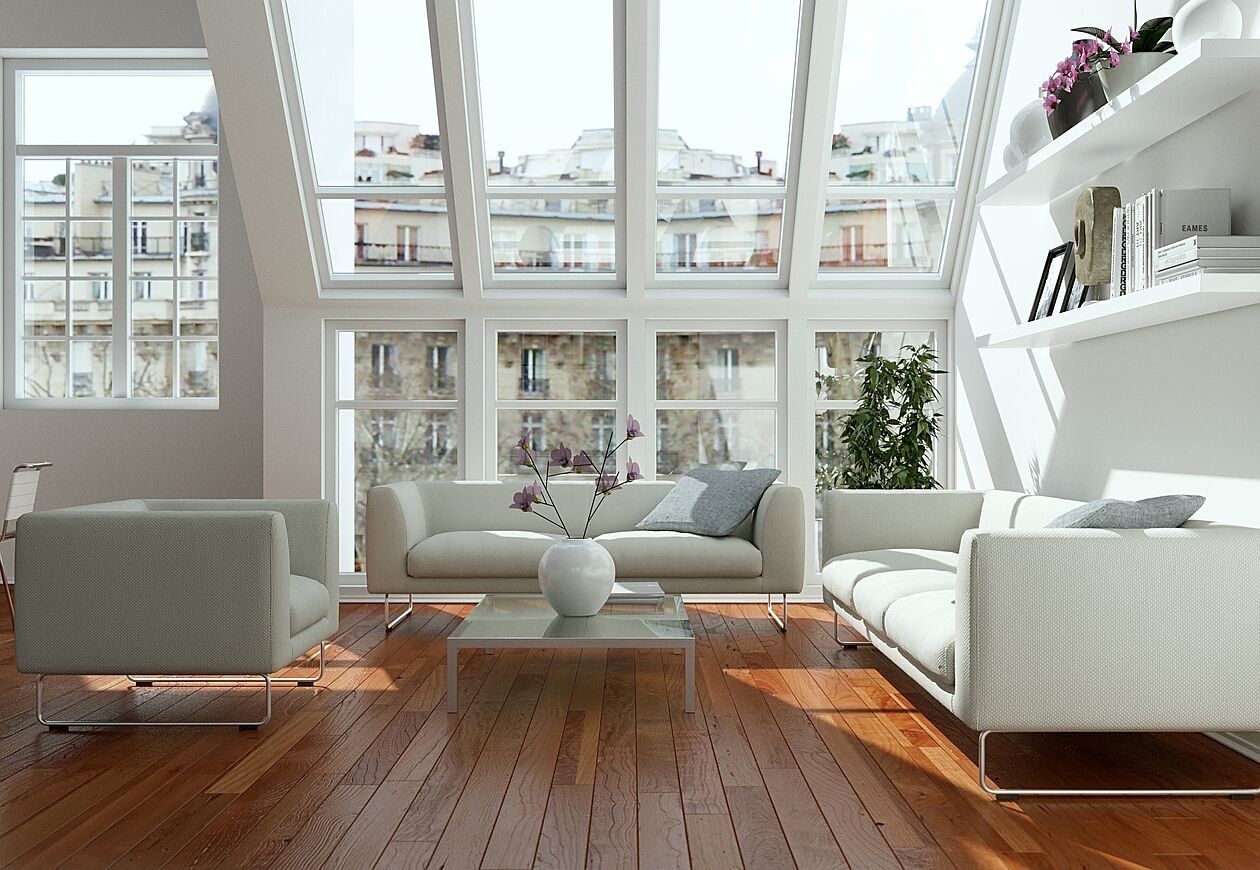 Modernes, lichtdurchflutetes Wohnzimmer mit großen Fensterfronten in einer Penthousewohnung mit Blick auf Stadthäuser.