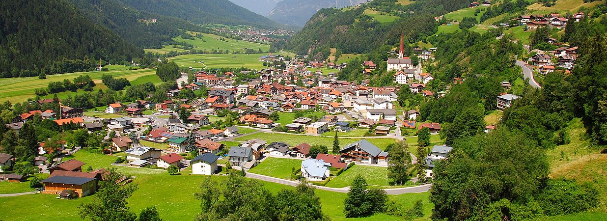 Dorf in Österreich mit Häusern und Bergen, aus der Vogelperspektive.