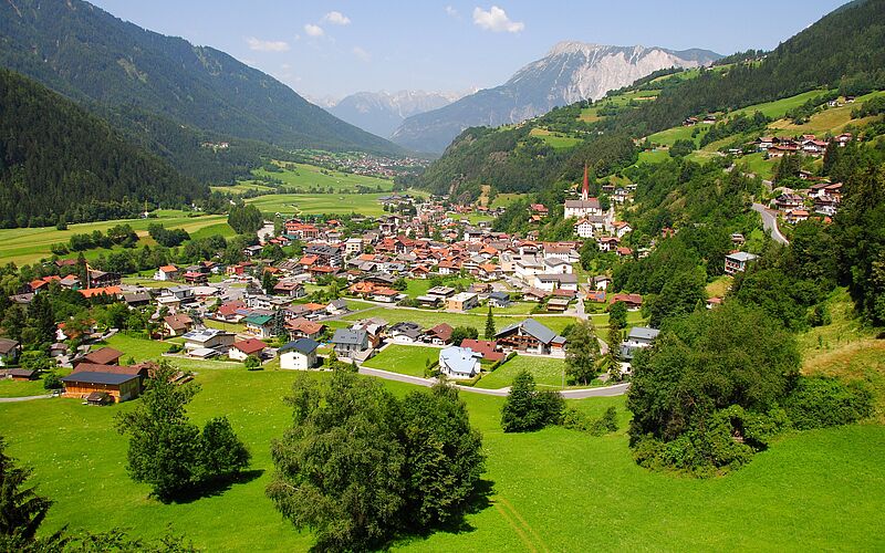 Dorf in Österreich mit Häusern und Bergen, aus der Vogelperspektive.
