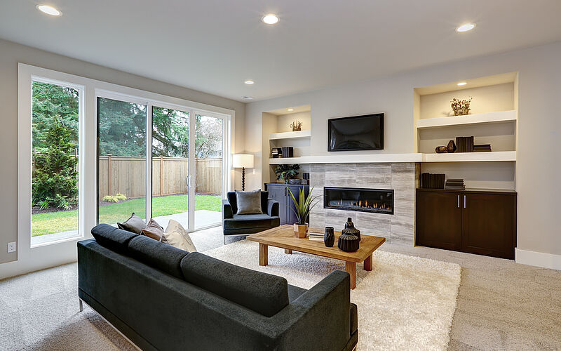 Modern eingerichtetes Wohnzimmer mit Kamin, großen Fenstern und hochwertiger Ausstattung.