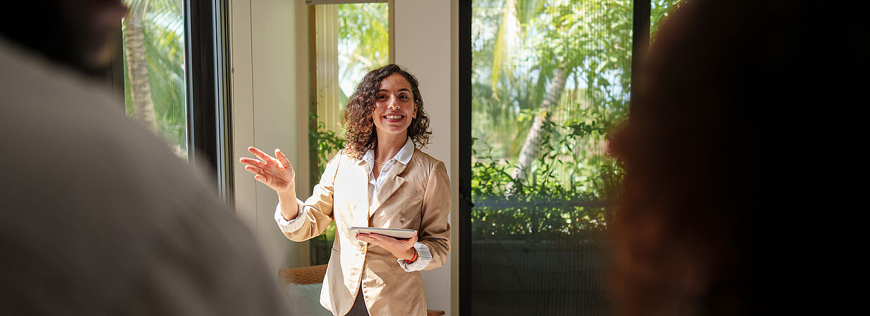 Eine Immobilienmaklerin spricht in einer Wohnung mit zwei Personen über eine Immobilie.