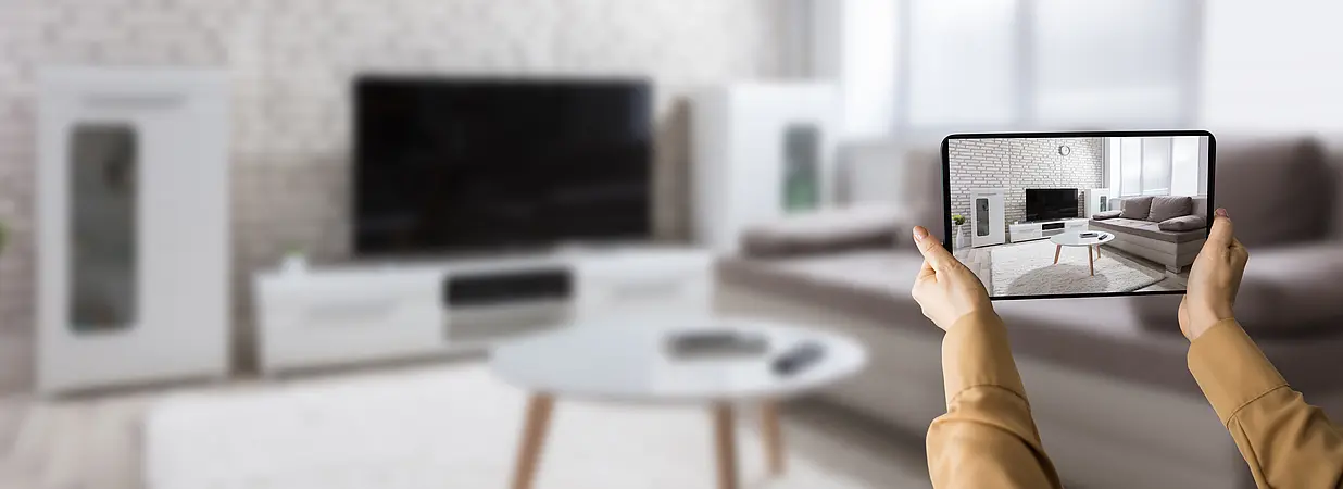 Eine Person betrachtet ein Wohnzimmer auf einem Tablet während einer virtuellen Immobilienbesichtigung.