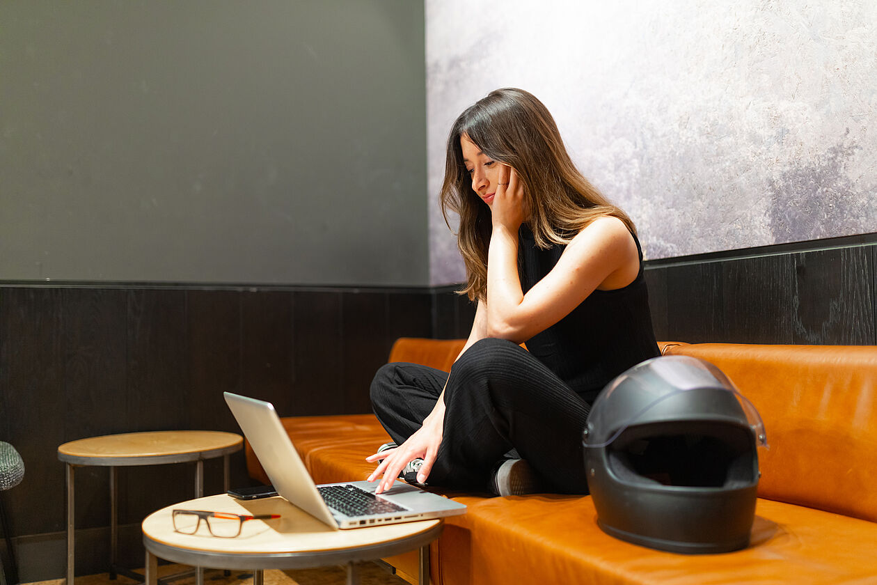 Frau am Laptop mit Motorradhelm