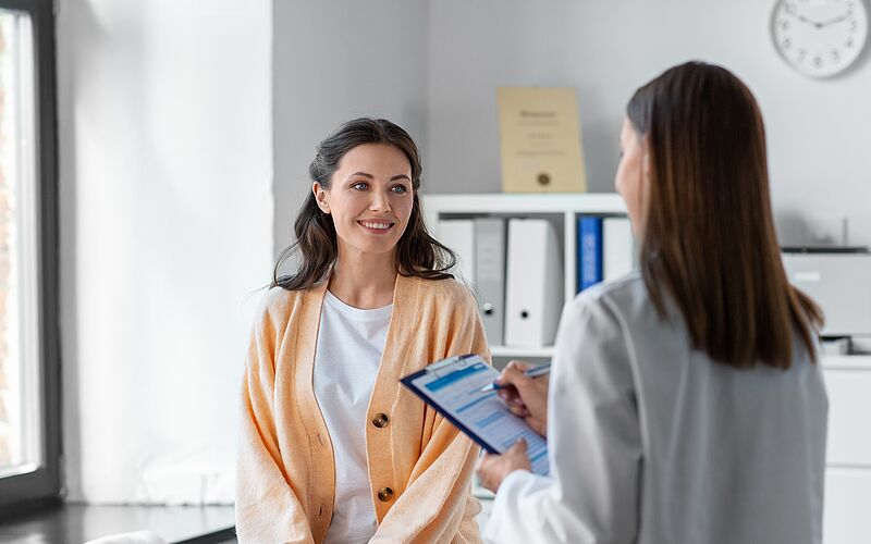 Arzt untersucht lächelnden Patienten mit Stethoskop, Symbol für Gesundheitskredit und Behandlung.