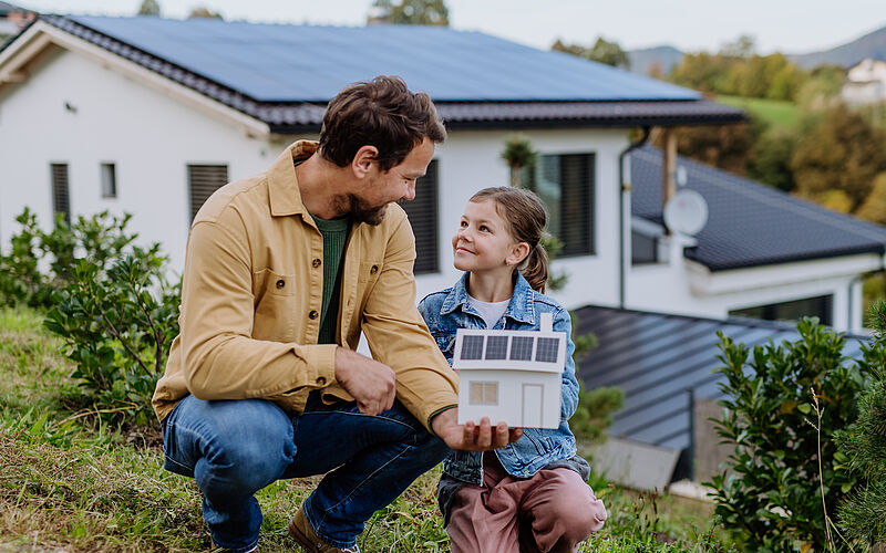 Papa mit Kind vor Haus