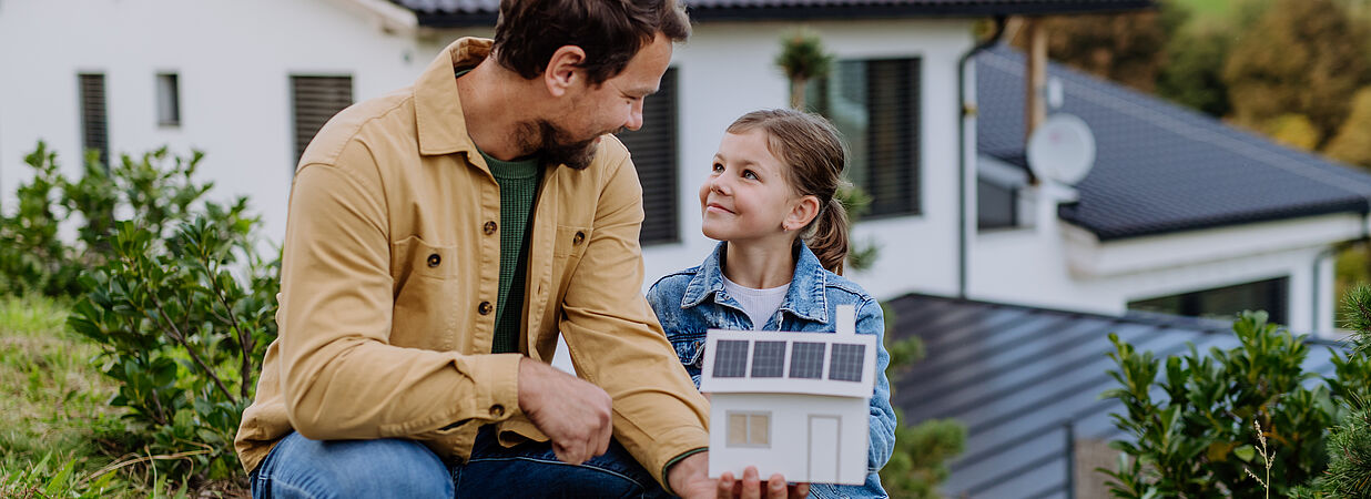 Papa mit Kind vor Haus