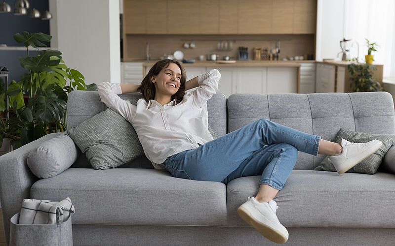 Frau liegt auf der Coach in ihrer 2-Zimmer-Wohnung
