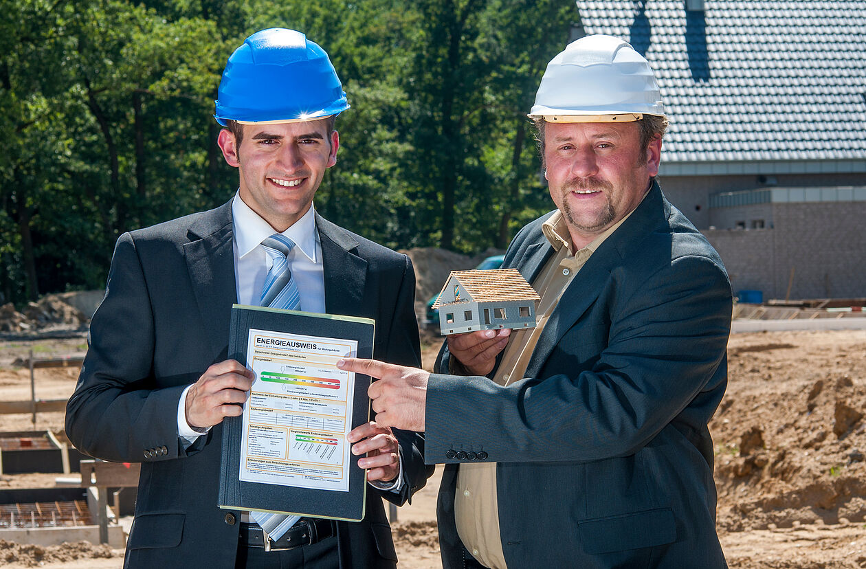 zwei Baumeister halten einen Energieausweis