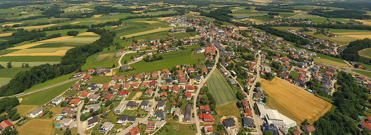 Luftaufnahme von Häusern, Grundstücken und Feldern in einer ländlichen Siedlung in Österreich.