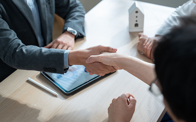 Ein Käufer und ein Verkäufer besiegeln den Immobilienverkauf mit einem Handschlag.