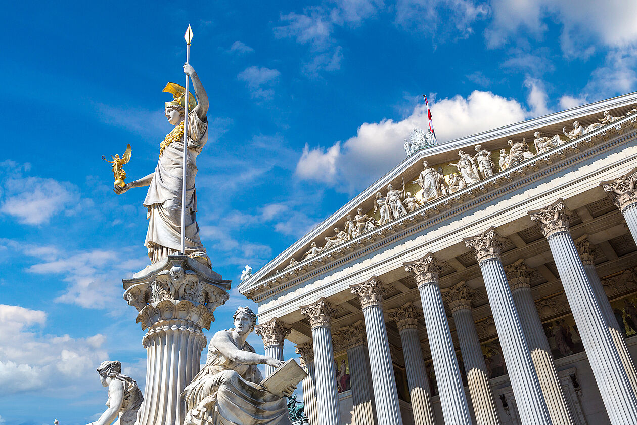 Das österreichische Parlamentsgebäude in Wien mit der Pallas-Athene-Statue bei Sonnenschein, Symbol für Gesetzgebung und staatliche Ordnung.