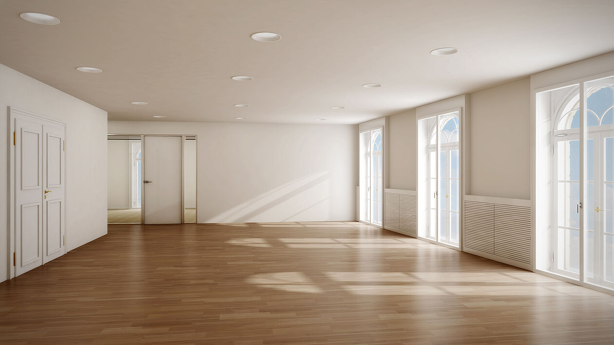 Heller, leerer Wohnraum mit großen Fenstern und Holzfußboden in moderner Immobilie.