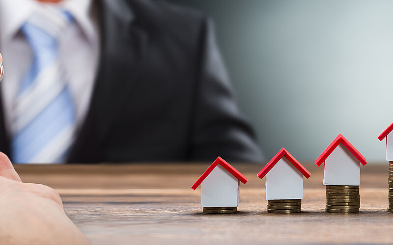 übergabe schlüssel und kleine häuser auf münzen