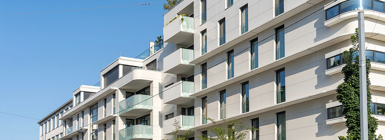 Modernes Mehrfamilienhaus mit Balkonen und Glasfassade als Symbol für Immobilieninvestment.