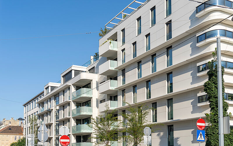 Modernes Mehrfamilienhaus mit Balkonen und Glasfassade als Symbol für Immobilieninvestment.