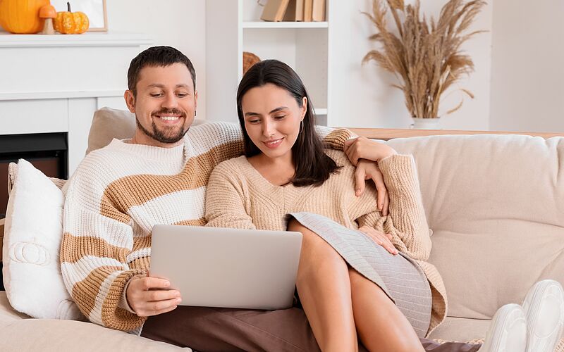 Paar auf Couch in Wohnung mit Laptop