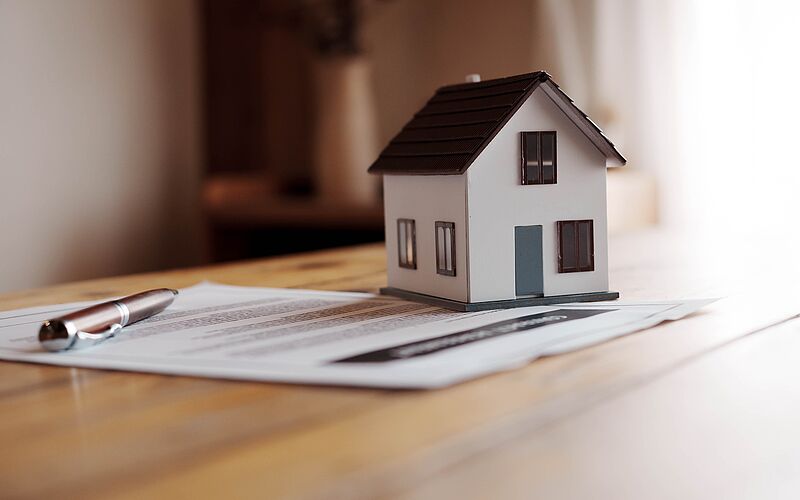 Modellhäuschen steht auf Unterlagen, die auf einem Tisch liegen.