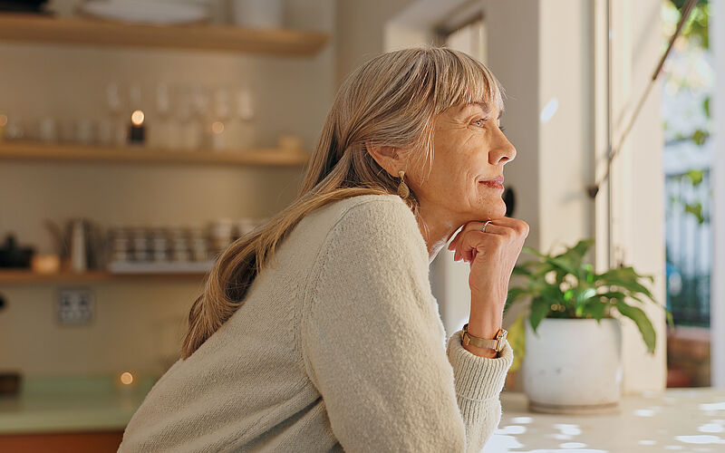 Frau sieht aus dem Fenster ihrer Einliegerwohnung.