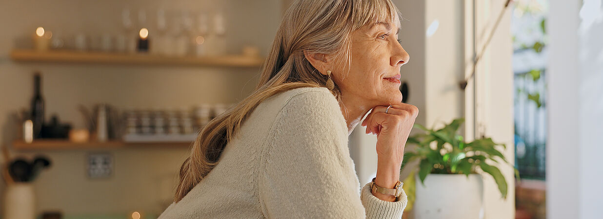 Frau sieht aus dem Fenster ihrer Einliegerwohnung.