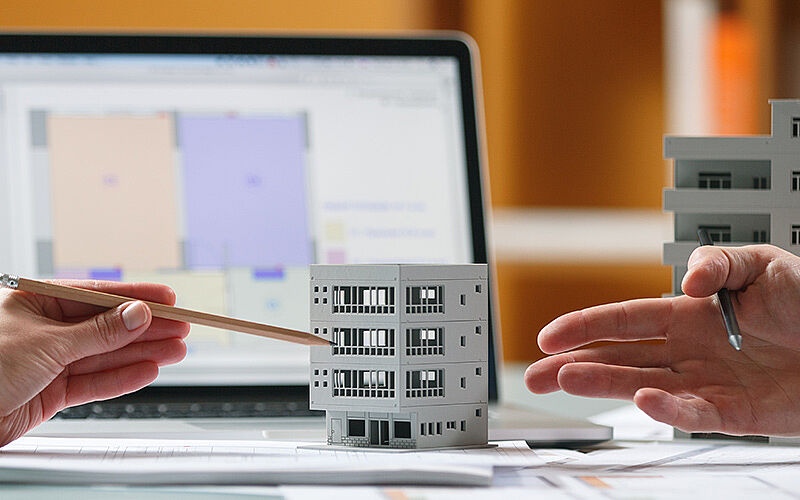 modell eines wohnblocks und pläne im hintergrund