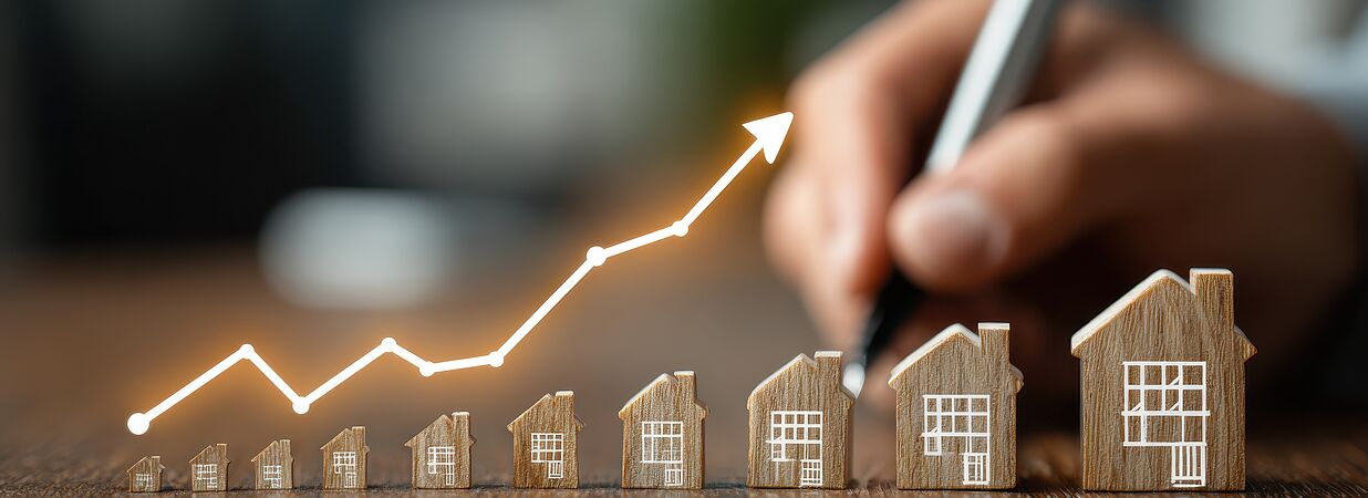 Steigende Zinsen bei Immobilienfinanzierungen symbolisiert durch Hausmodelle und Wachstumskurve