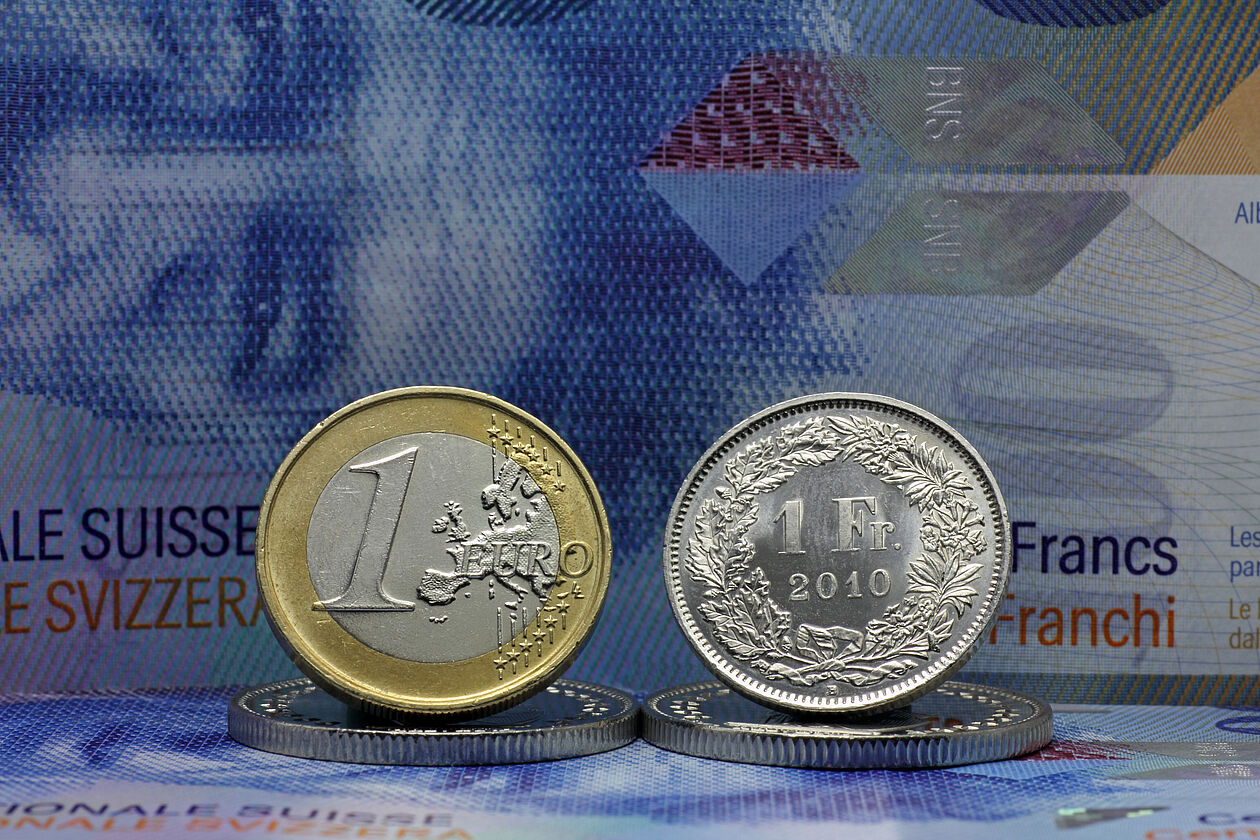 Werden Euro-Schulden mit Franken-Einnahmen getilgt, werden Kredite bei schwachem Franken teurer. 1 Euro und 1 Schweizer Franken stehen nebeneinander.