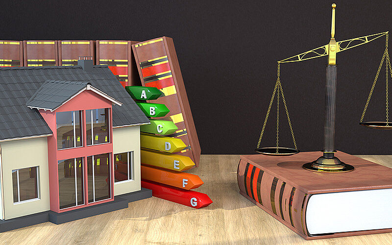 modellhaus mit gesetzesbüchern im hintergrund, waage und energiestufen
