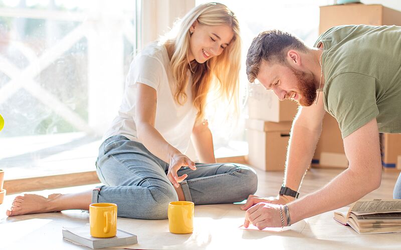 Paar am Boden sitzend bei der Planung des Hausbaus