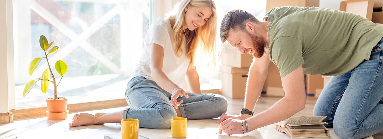 Paar am Boden sitzend bei der Planung des Hausbaus