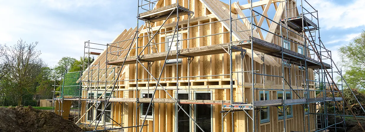 Einfamilienhaus im Rohbau mit Gerüst auf einer Baustelle.