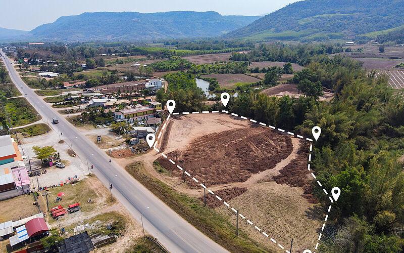 Luftaufnahme eines abgegrenzten, baureifen Grundstücks an einer Straße mit umliegender Bebauung