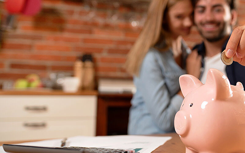pärchen wirft geld in sparschwein