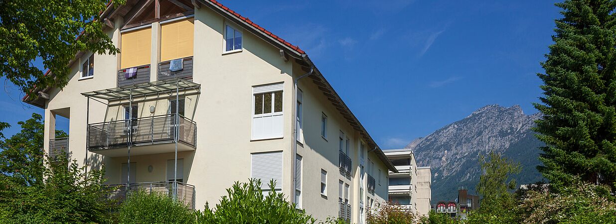 Mehrfamilienhaus in Österreich mit Balkonen vor Alpenkulisse – Symbol für WEG-Finanzierung.