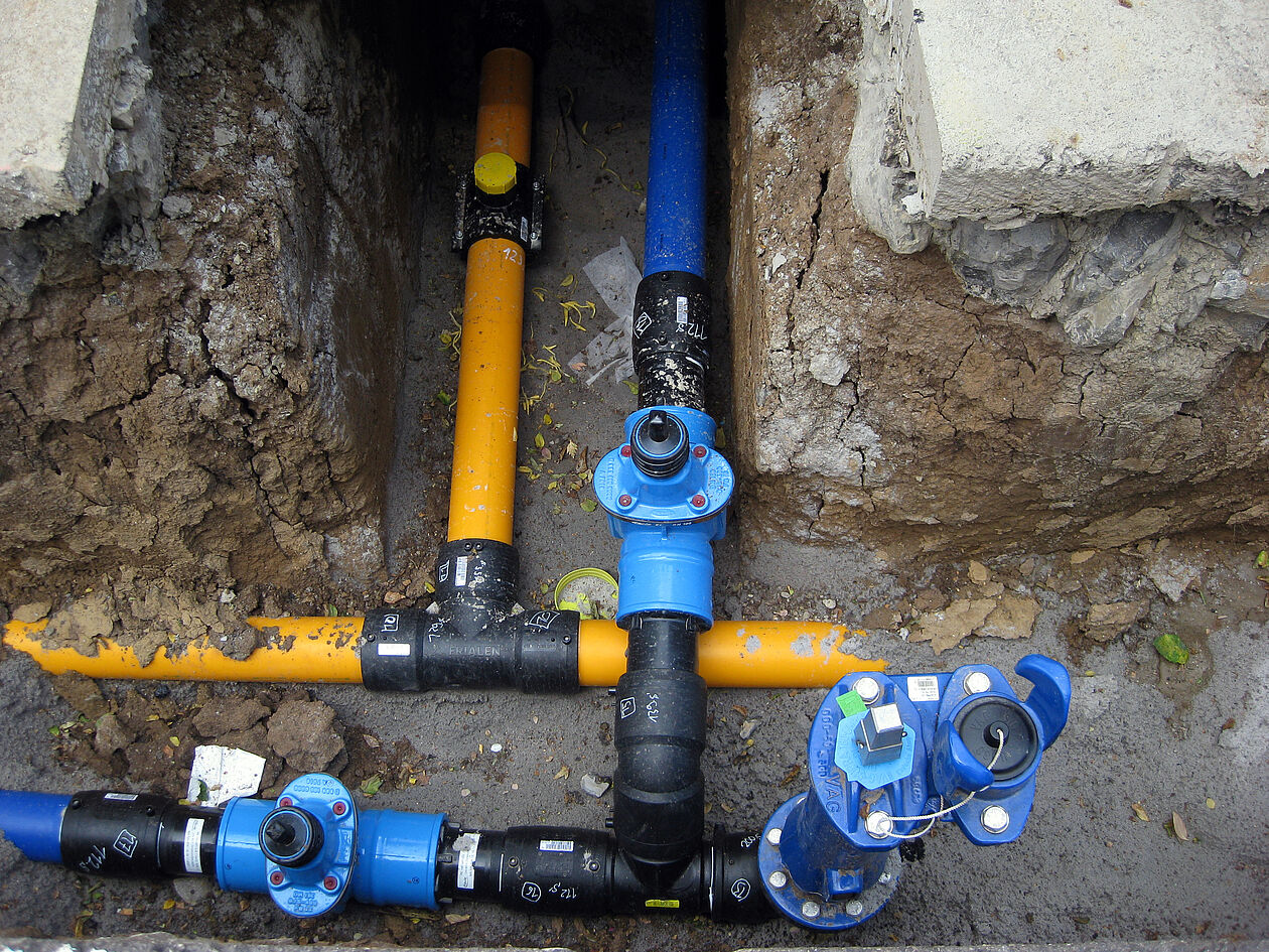 Freigelegte Wasser- und Versorgungsleitungen zeigen die Erschließung eines Baugrundstücks.