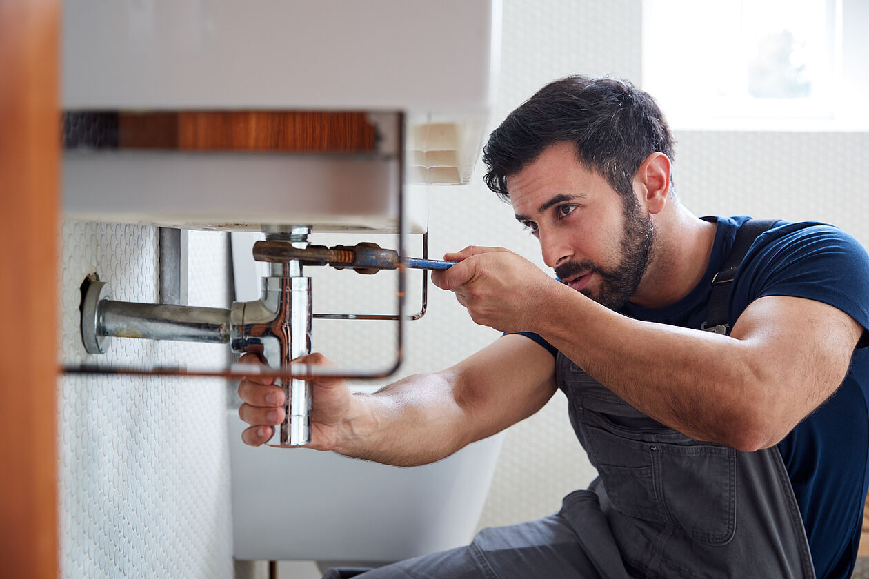 Ein Handwerker führt Arbeiten an den Sanitäranlagen einer Wohnung durch.