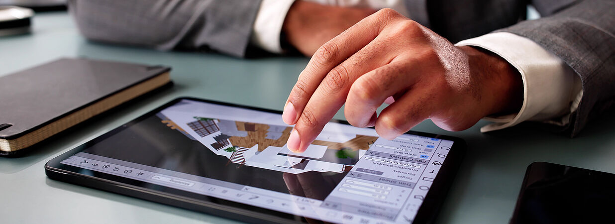 Architekt zeigt digitalen Haus-Grundriss auf Tablet in moderner Büro-Umgebung.