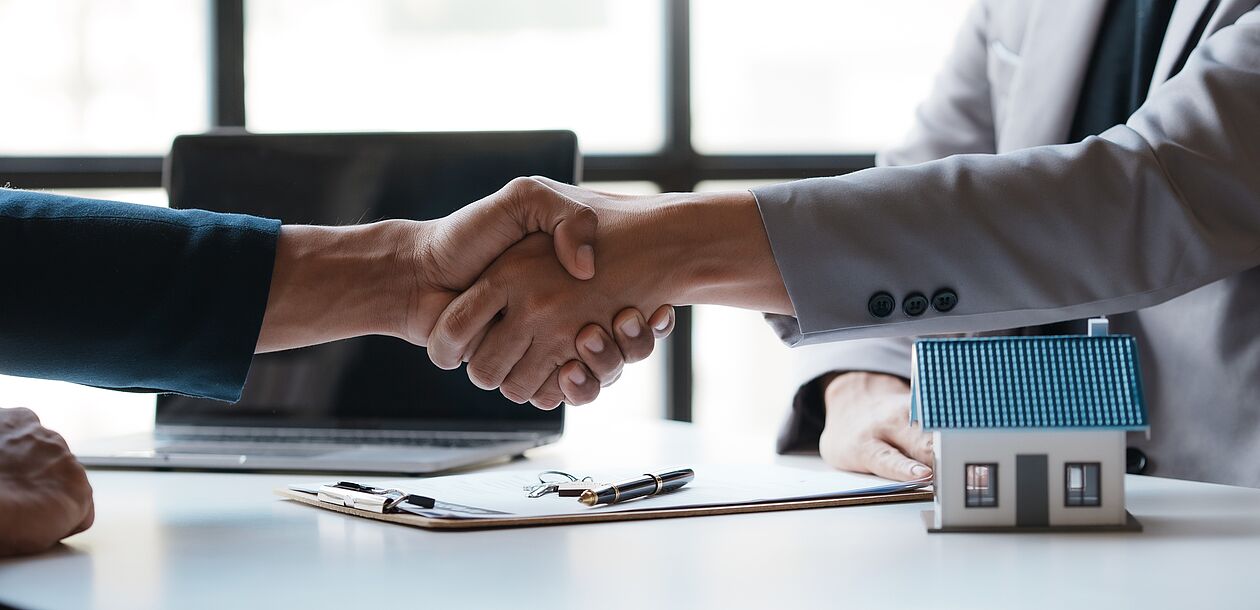 Handschlag hinter kleinem Haus