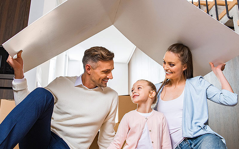 glückliche familie unter kartonhaus
