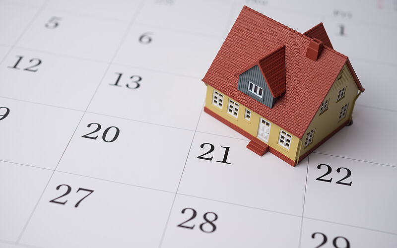 Ein Plastikhäuschen steht auf einem Kalender.