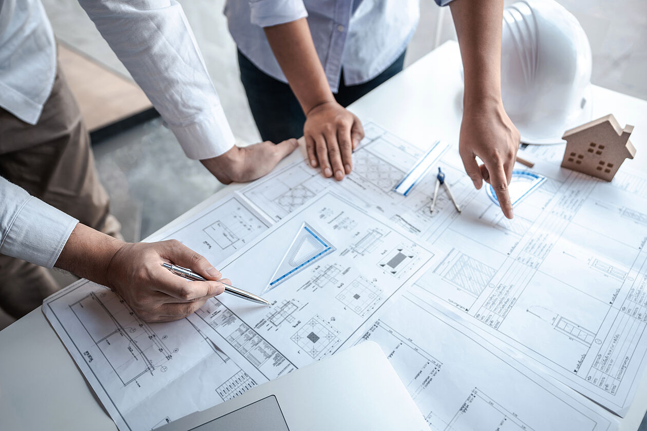 Personen prüfen Baupläne und besprechen Details an einem Tisch.