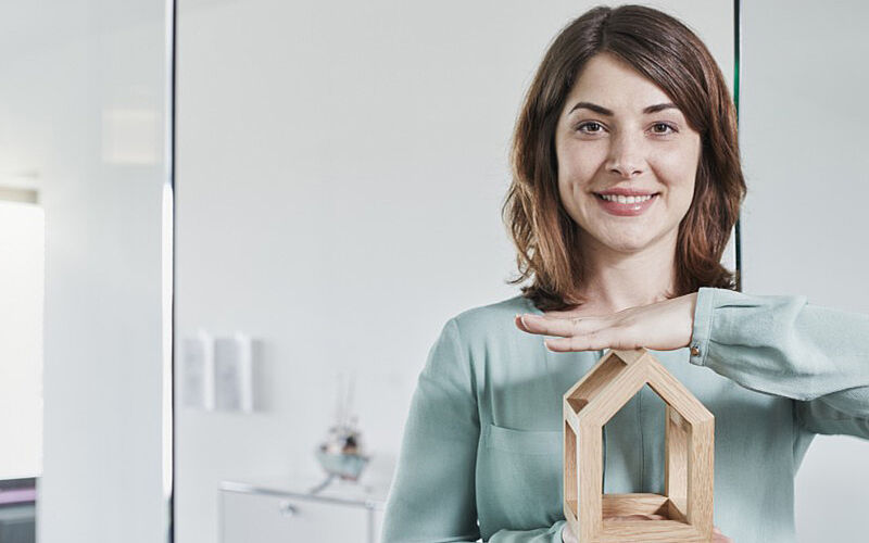 frau mit holzhaus in der hand