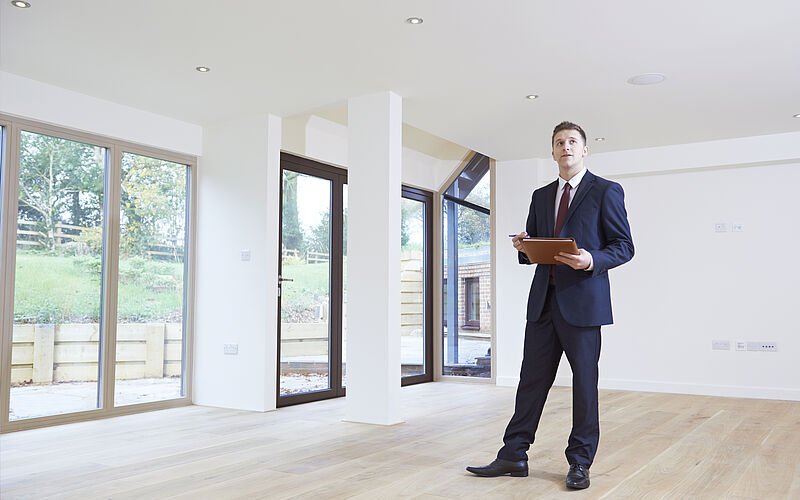 immobilienmakler zeigt wohnung