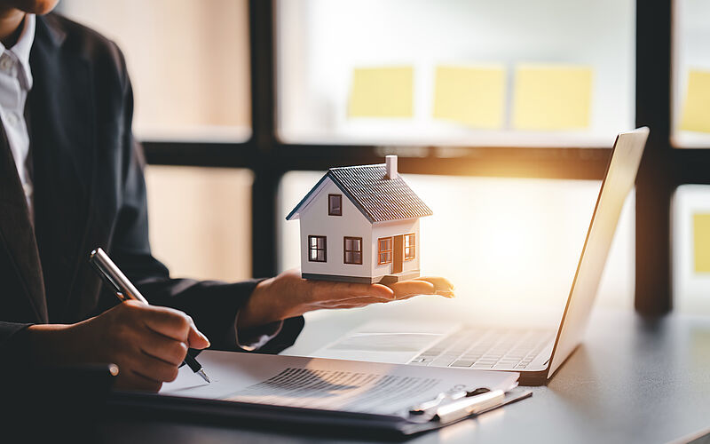 mannmit laptop hält kleines haus