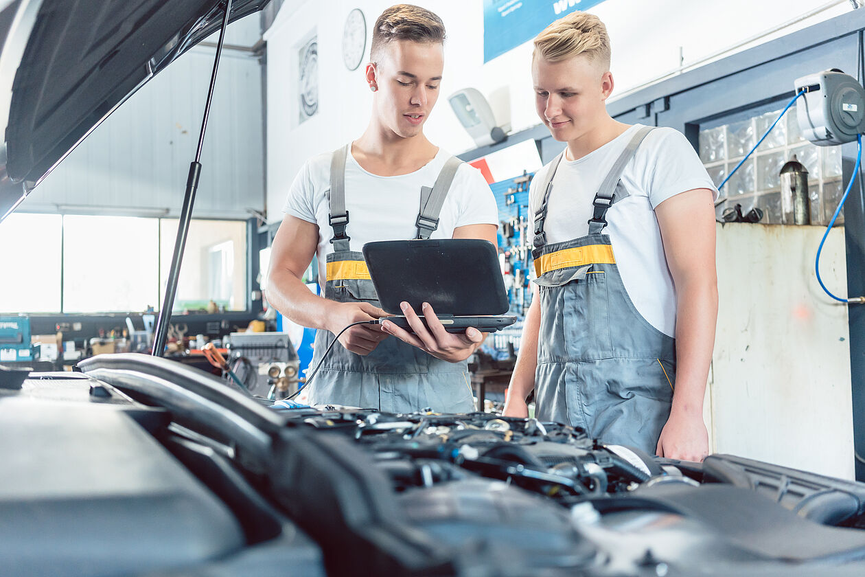 zwei lehrlinge in der autowerkstatt