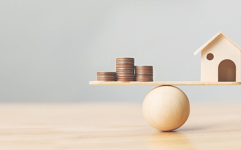 holzhaus und münzen auf der waage